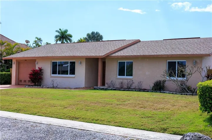 Ranch-style house with stucco siding, a garage, a front yard, and roof with shingles
