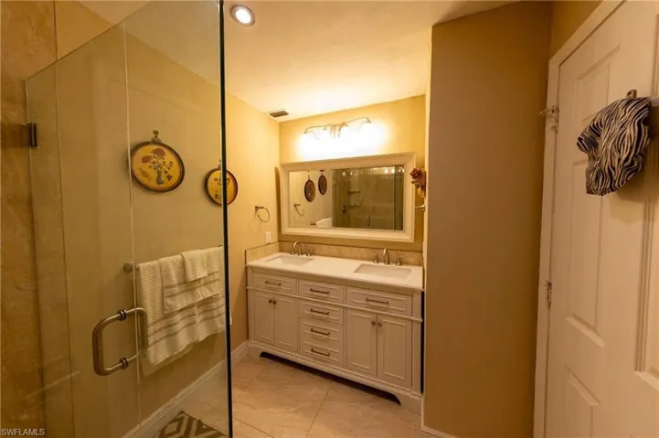 Full bath featuring a shower stall, double vanity, light tile patterned floors, and recessed lighting