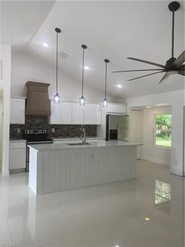 Kitchen with fridge, a sink, range, lofted ceiling, and ventilation hood