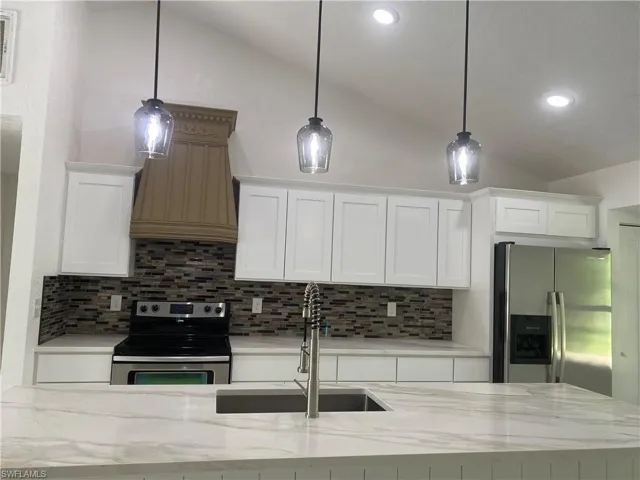 Kitchen featuring stainless steel fridge with ice dispenser, a sink, white cabinets, a ceiling fan, and high vaulted ceiling
