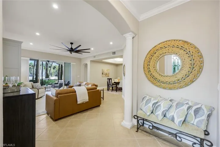 Living room featuring crown molding, decorative columns, arched walkways, recessed lighting, and light tile patterned flooring