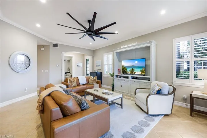 Living area featuring ornamental molding, a ceiling fan, arched walkways, light tile patterned floors, and recessed lighting