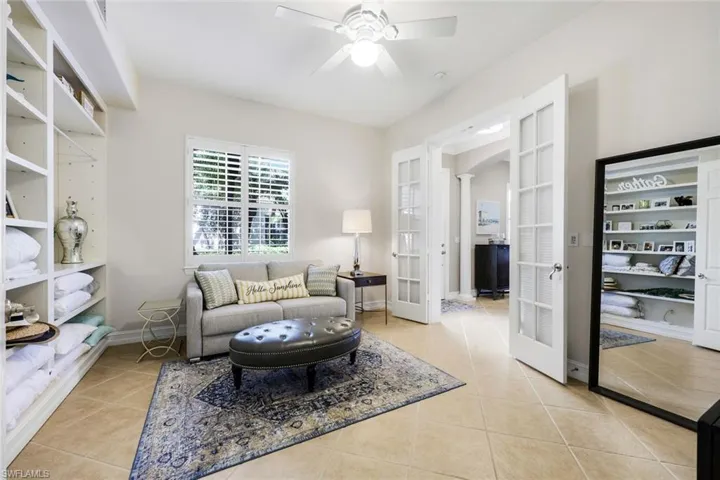 Living room with french doors, light tile patterned flooring, arched walkways, and a ceiling fan