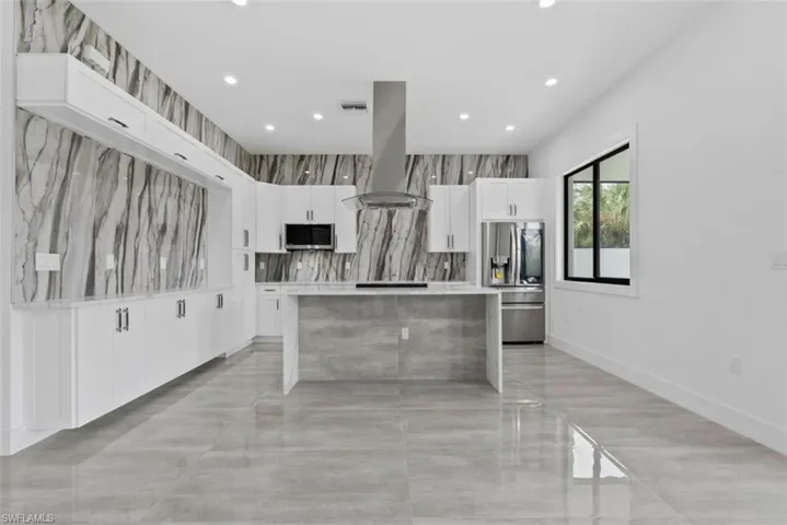 Kitchen featuring island range hood, a kitchen island, white cabinets, and stainless steel appliances