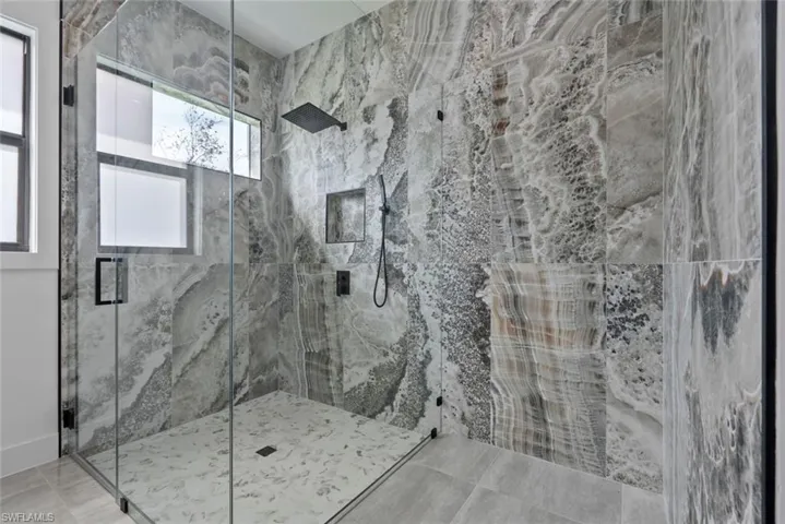 Bathroom featuring a shower with shower door and a wealth of natural light