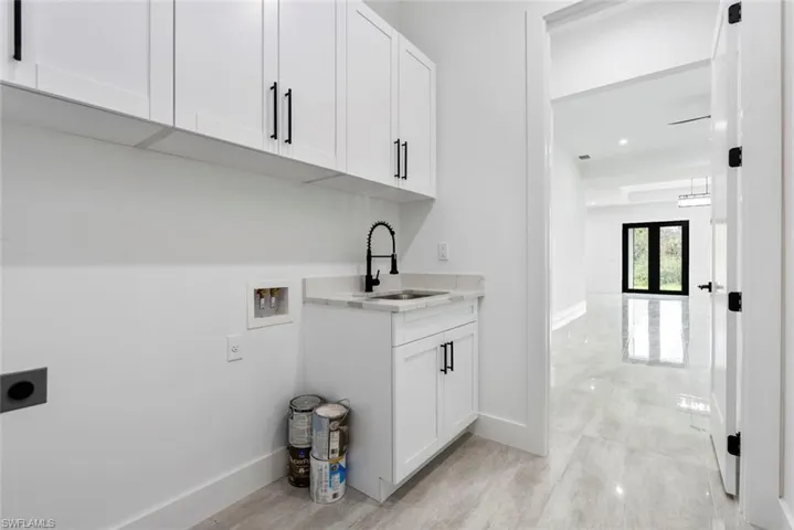 Laundry room with cabinets, hookup for a washing machine, hookup for an electric dryer, french doors, and sink