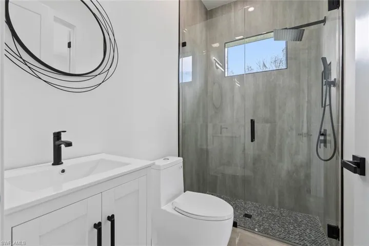 Bathroom featuring toilet, vanity, and a shower with door