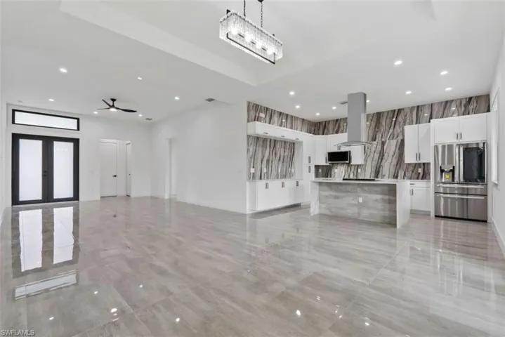Unfurnished living room featuring ceiling fan with notable chandelier