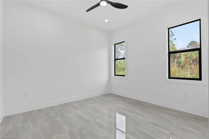 Empty room featuring ceiling fan and a wealth of natural light