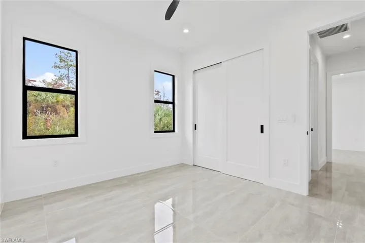 Unfurnished bedroom featuring a closet, ceiling fan, light tile patterned flooring, and multiple windows