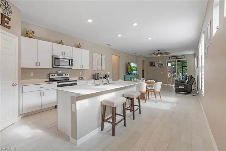 Kitchen with appliances with stainless steel finishes, white cabinetry, sink, and a center island with sink