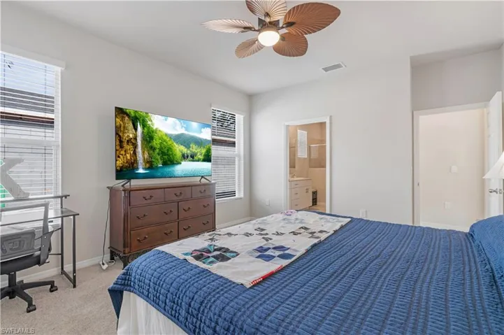 Bedroom with light colored carpet, connected bathroom, and ceiling fan