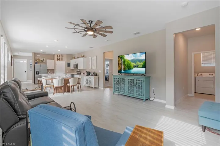 Living room with washing machine and dryer, ceiling fan, and light hardwood / wood-style flooring