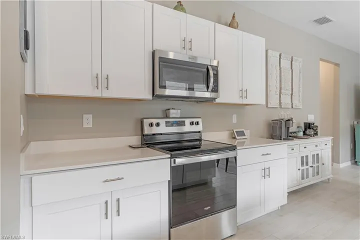 Kitchen featuring white cabinets, light tile floors, and appliances with stainless steel finishes