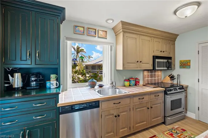 Kitchen with stainless steel appliances, light wood-style flooring, tile counters, and recessed lighting