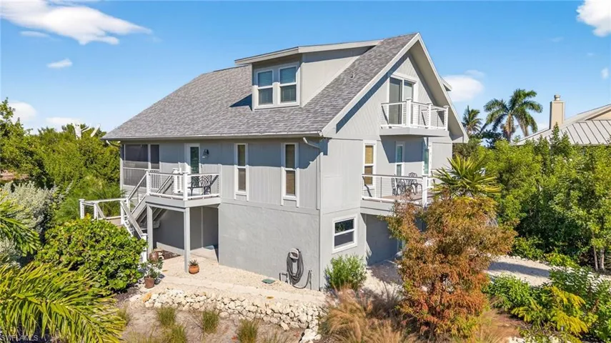 Rear view of property with stairs, a shingled roof, and a balcony