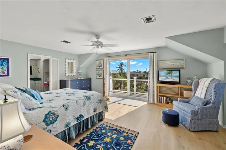 Bedroom with wood finished floors, ceiling fan, vaulted ceiling, and ensuite bathroom