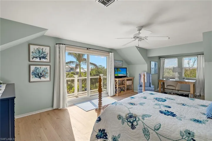 Bedroom featuring access to outside, light wood-style floors, ceiling fan, vaulted ceiling, and an office area