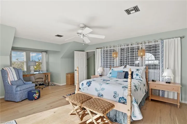 Bedroom with light wood-style flooring, ceiling fan, and an office area