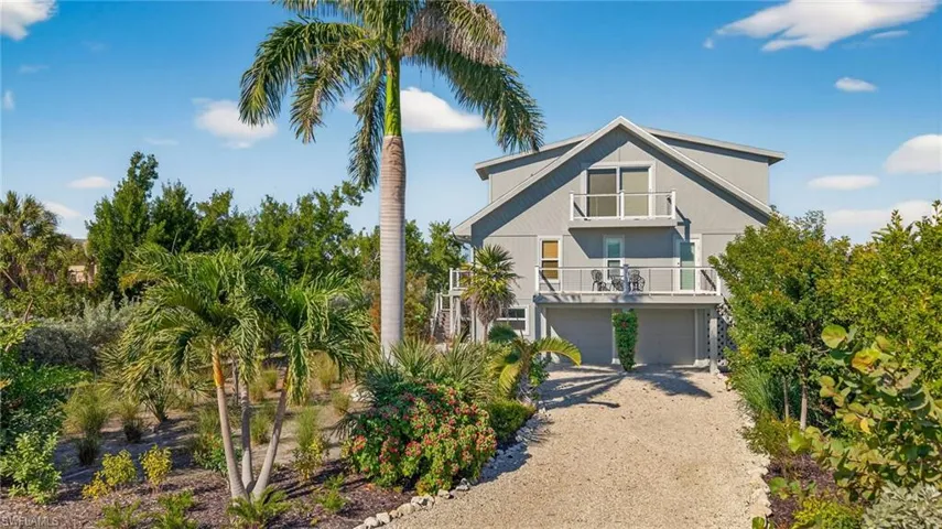 Coastal home featuring a balcony, driveway, and an attached garage