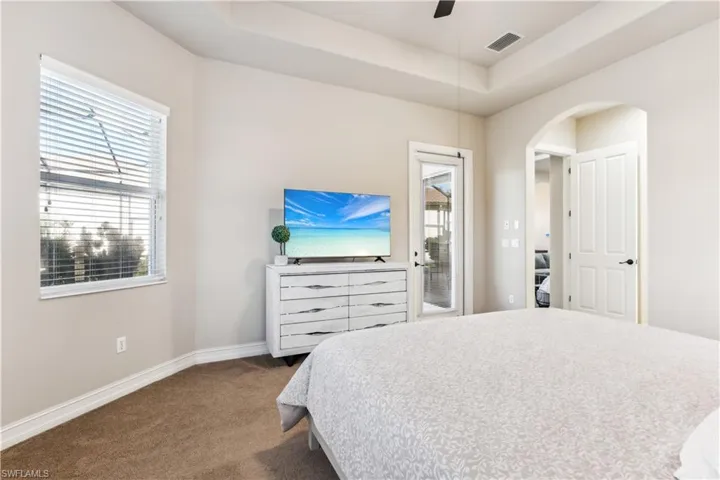 Bedroom with multiple windows, access to outside, arched walkways, and dark carpet