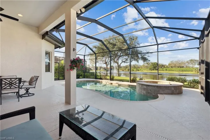 View of pool featuring a sunroom, a patio area, a lanai, a water view, and a pool with connected hot tub