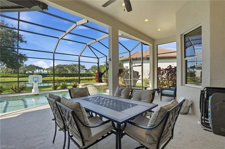 View of patio featuring a lanai, a sunroom, ceiling fan, a water view, and outdoor dining space