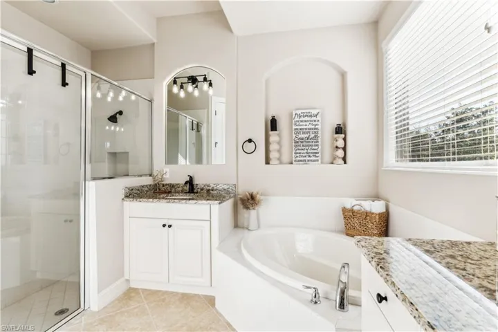Full bathroom featuring vanity, a stall shower, a bath, and light tile patterned floors