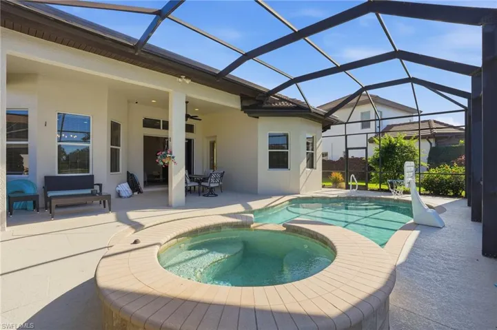 View of swimming pool with a sunroom, glass enclosure, a pool with connected hot tub, and a patio area