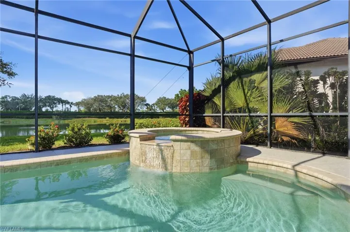 View of swimming pool with a sunroom, a lanai, a pool with connected hot tub, and a water view