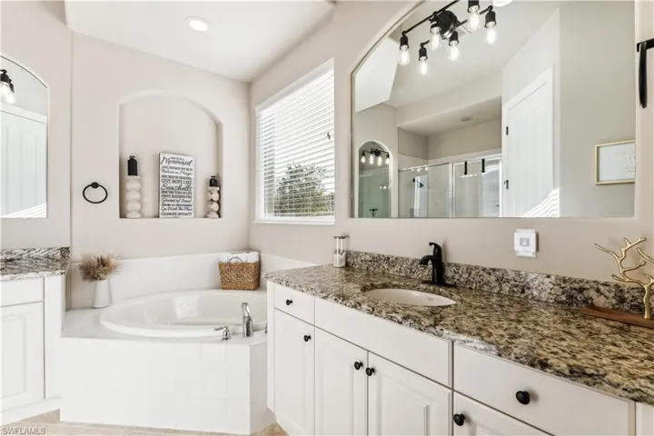 Full bathroom with vanity, a garden tub, and a shower stall