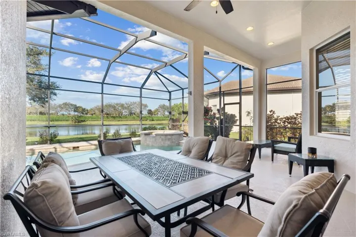 View of patio featuring a lanai, a ceiling fan, a water view, a sunroom, and outdoor dining area