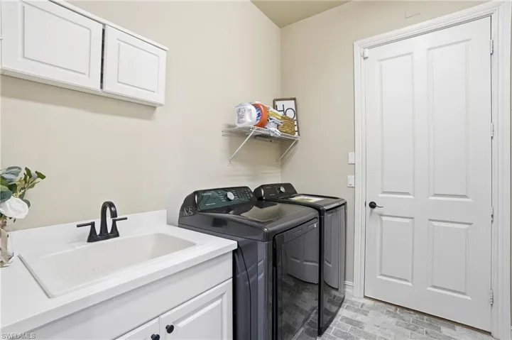 Laundry room with cabinet space, washer and clothes dryer, and brick patterned flooring