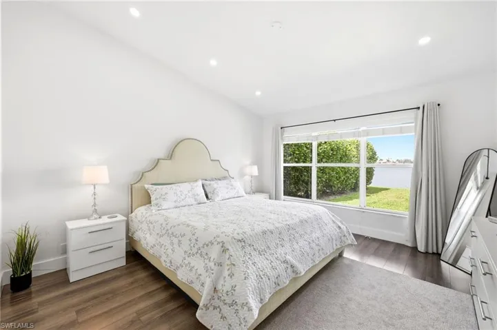 Bedroom with dark wood-style flooring, recessed lighting, vaulted ceiling, and a water view