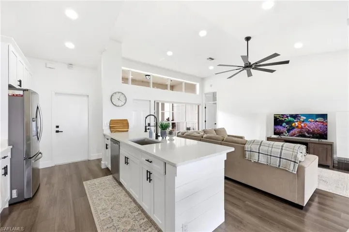 Kitchen with white cabinetry, open floor plan, dark wood-style floors, stainless steel appliances, and a peninsula