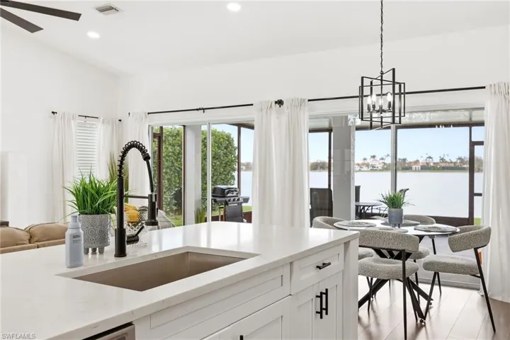 Kitchen with open floor plan, light stone counters, white cabinetry, a chandelier, and a ceiling fan