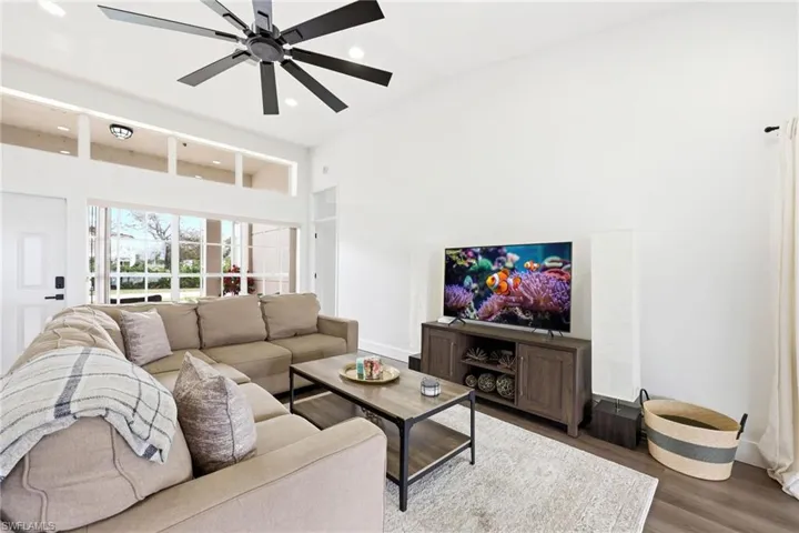 Living room with wood finished floors, recessed lighting, a ceiling fan, and lofted ceiling
