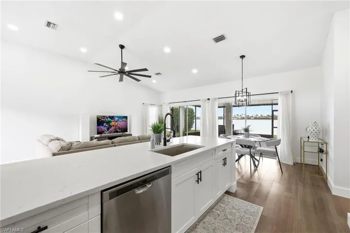 Kitchen featuring light stone countertops, dishwasher, open floor plan, dark wood finished floors, and ceiling fan