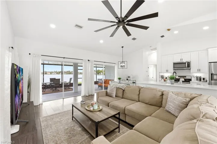 Living area with dark wood finished floors, recessed lighting, a ceiling fan, vaulted ceiling, and a water view