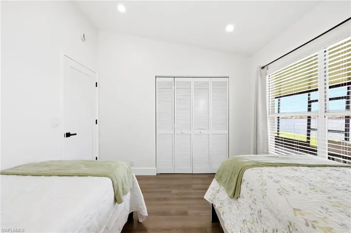Bedroom with vaulted ceiling, recessed lighting, dark wood-type flooring, and a closet