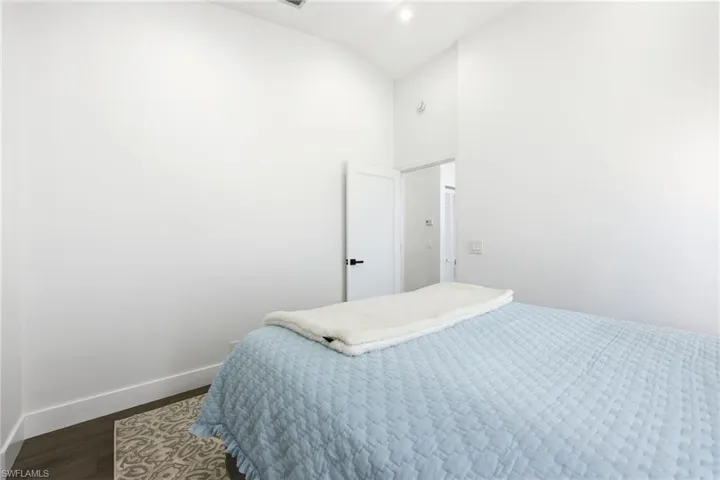 Bedroom with vaulted ceiling, dark wood-style flooring, and recessed lighting