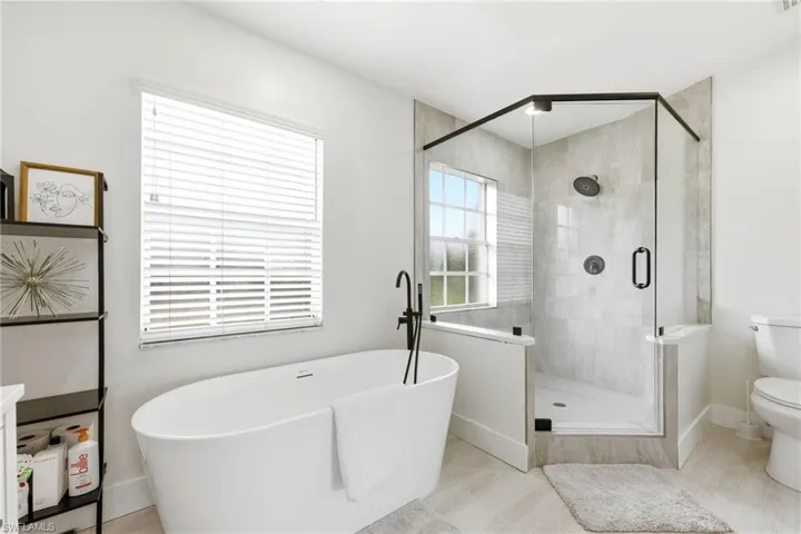 Full bath featuring a soaking tub, a shower stall, and light wood finished floors