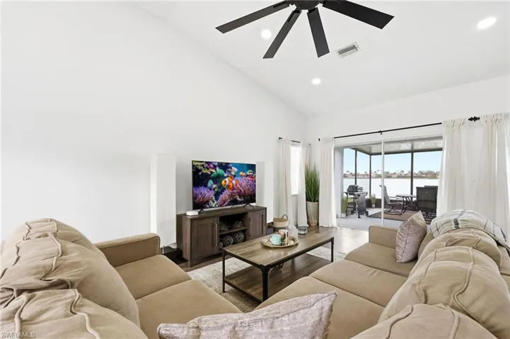 Living area with wood finished floors, ceiling fan, vaulted ceiling, and recessed lighting