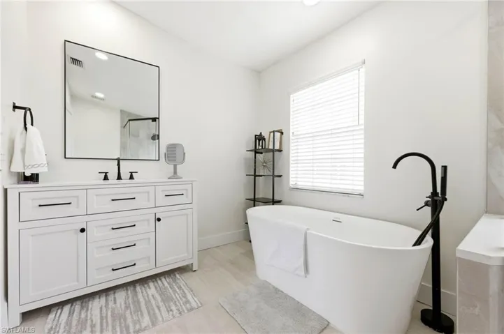 Full bathroom featuring vanity, a soaking tub, and recessed lighting