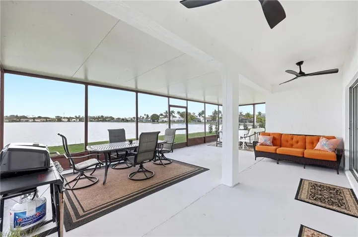 Sunroom featuring a water view, a ceiling fan, an outdoor living / dining area, and a patio
