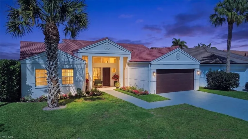 View of front of property with a lawn, a garage, and a tile roof