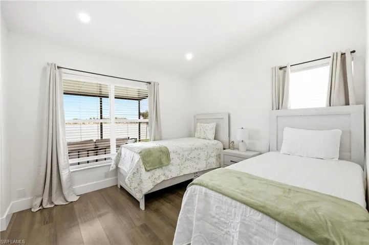 Bedroom featuring multiple windows, dark wood-style flooring, vaulted ceiling, and recessed lighting
