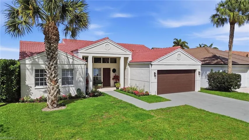 View of front of house with a front yard, stucco siding, an attached garage, and a tiled roof