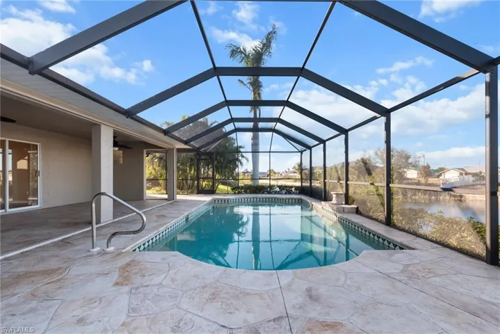 View of pool with a water view, a patio area, ceiling fan, and a lanai