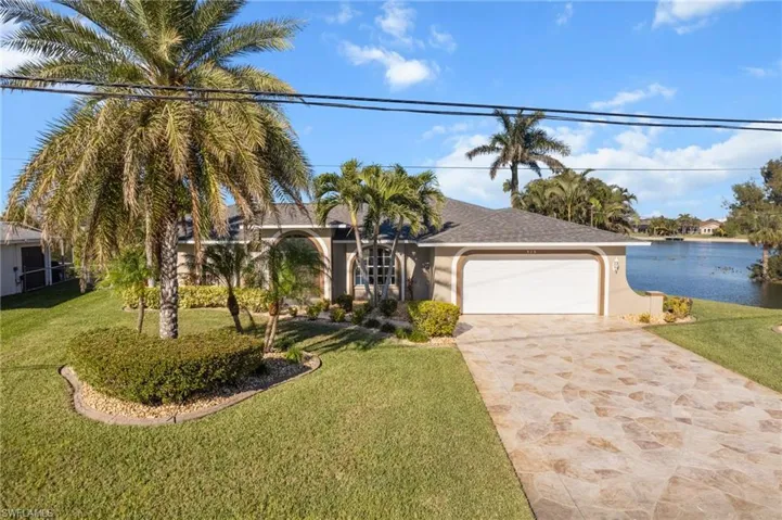 View of front of home with a front yard, a water view, and a garage